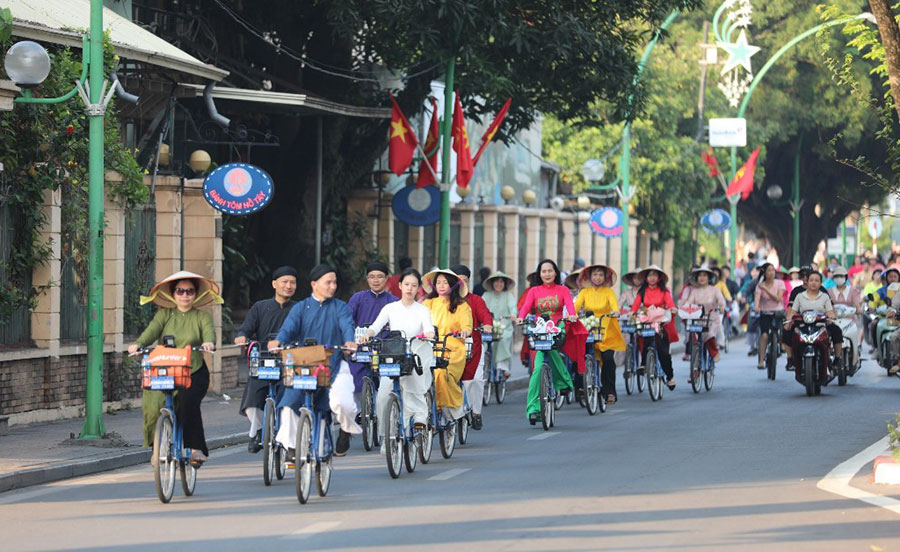 Ao dai parade on bicycle through Hanoi streets.